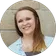 A woman is smiling in a circle in front of a brick wall.