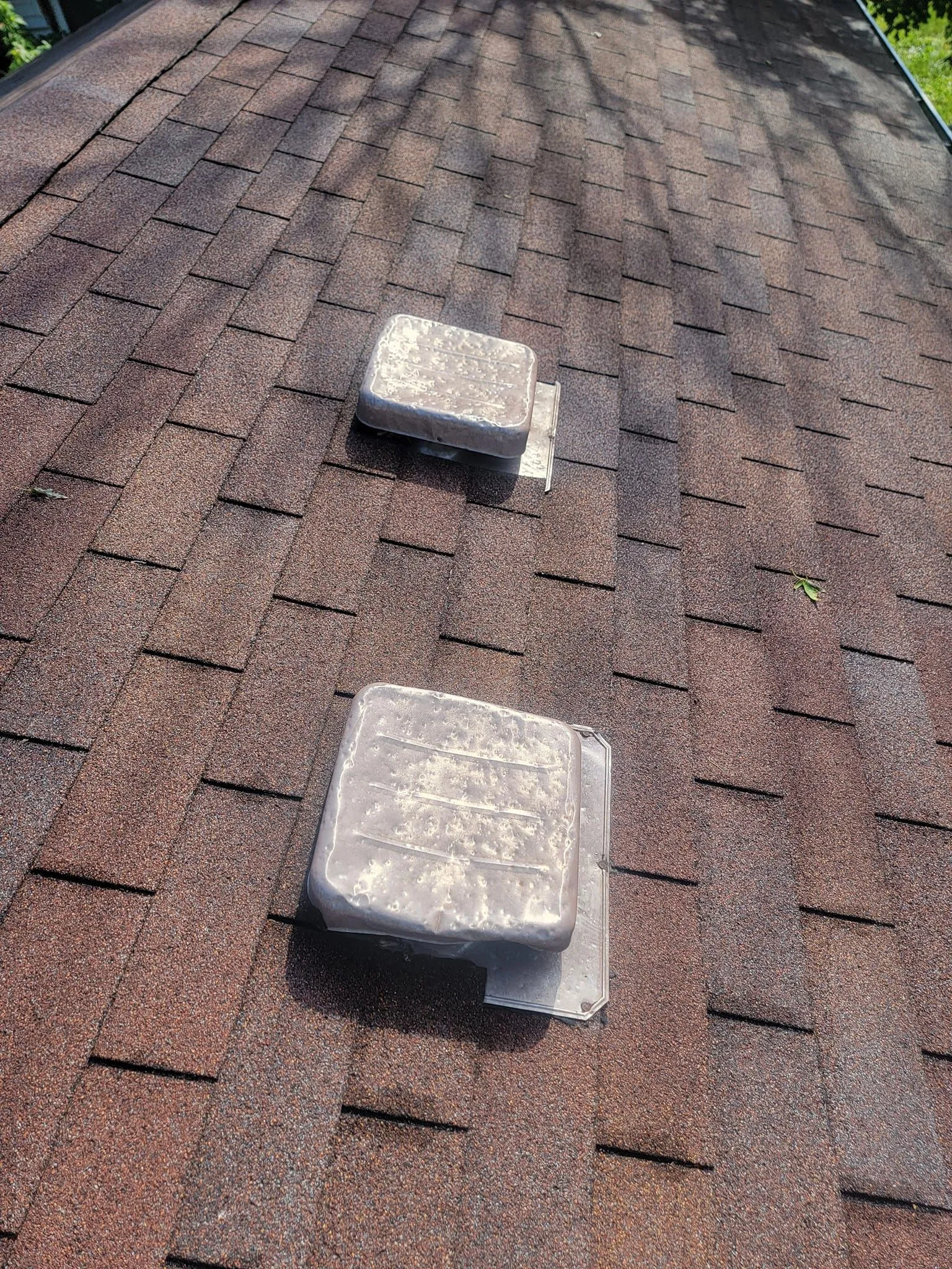 There are two vents on the roof of a house.