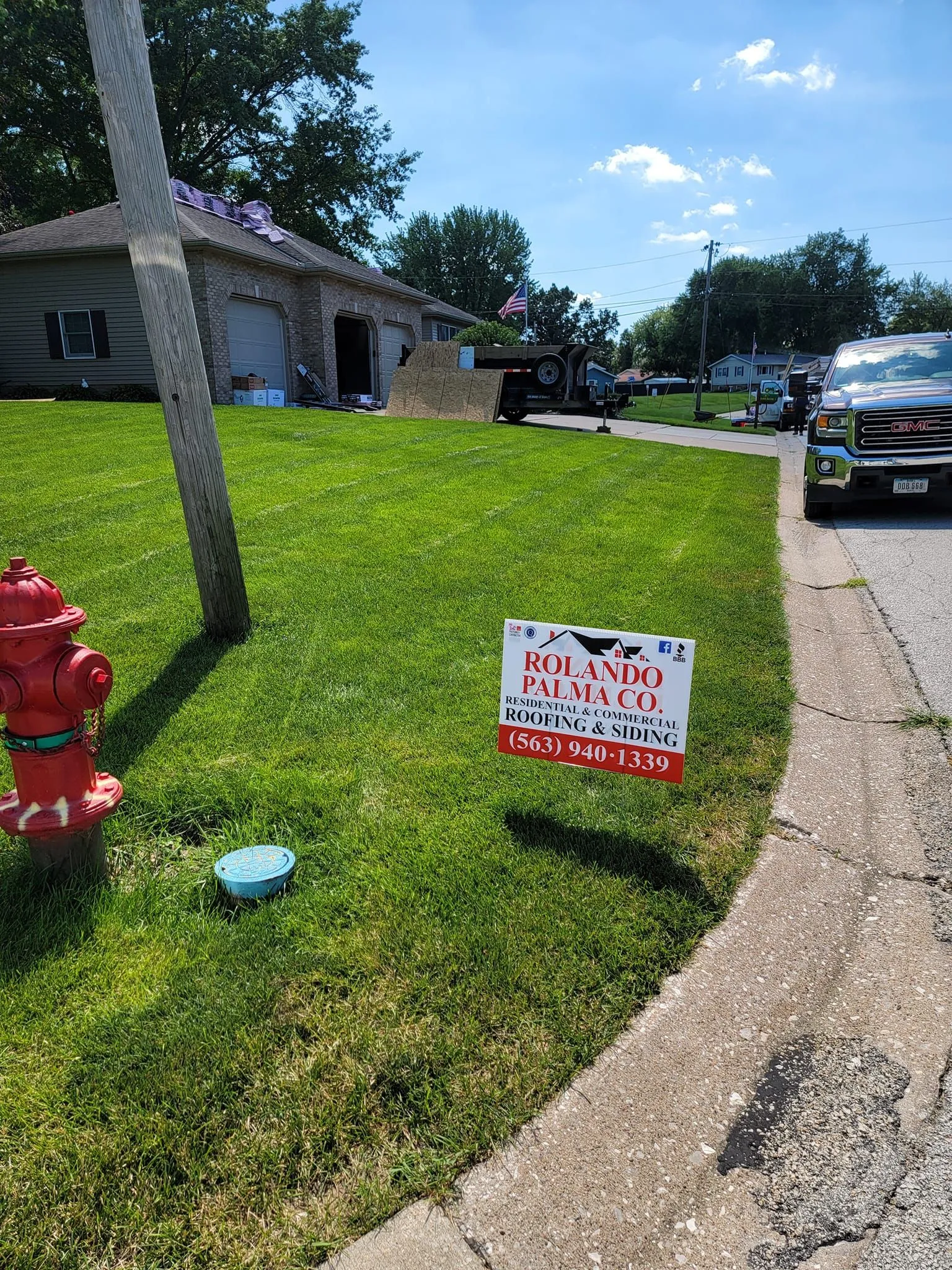 Rolando Palma Co. roofing and siding yard sign on a front lawn