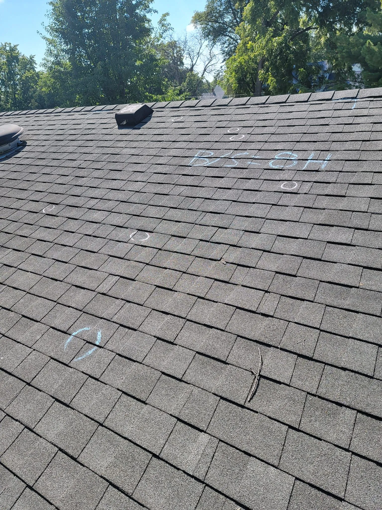 Gray shingle roof with hail damage circled in chalk
