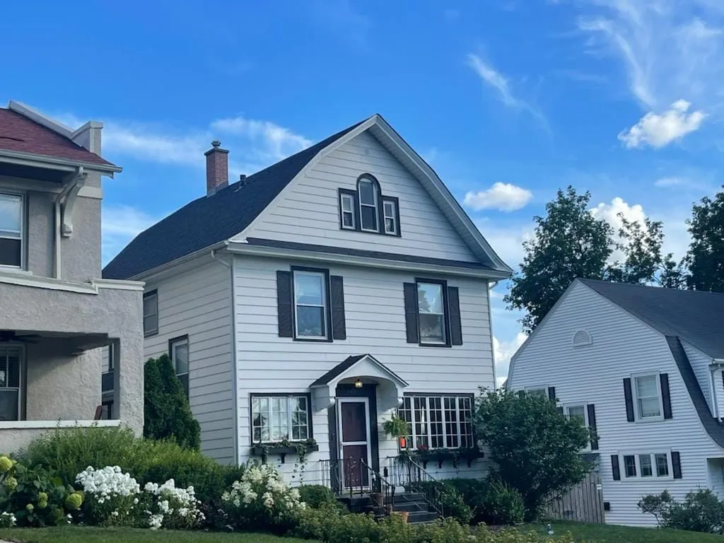 A white house with a black roof completed by Rolando Roofing