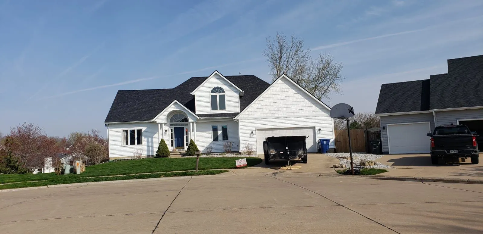 A white house with a black roof completed by Rolando Roofing